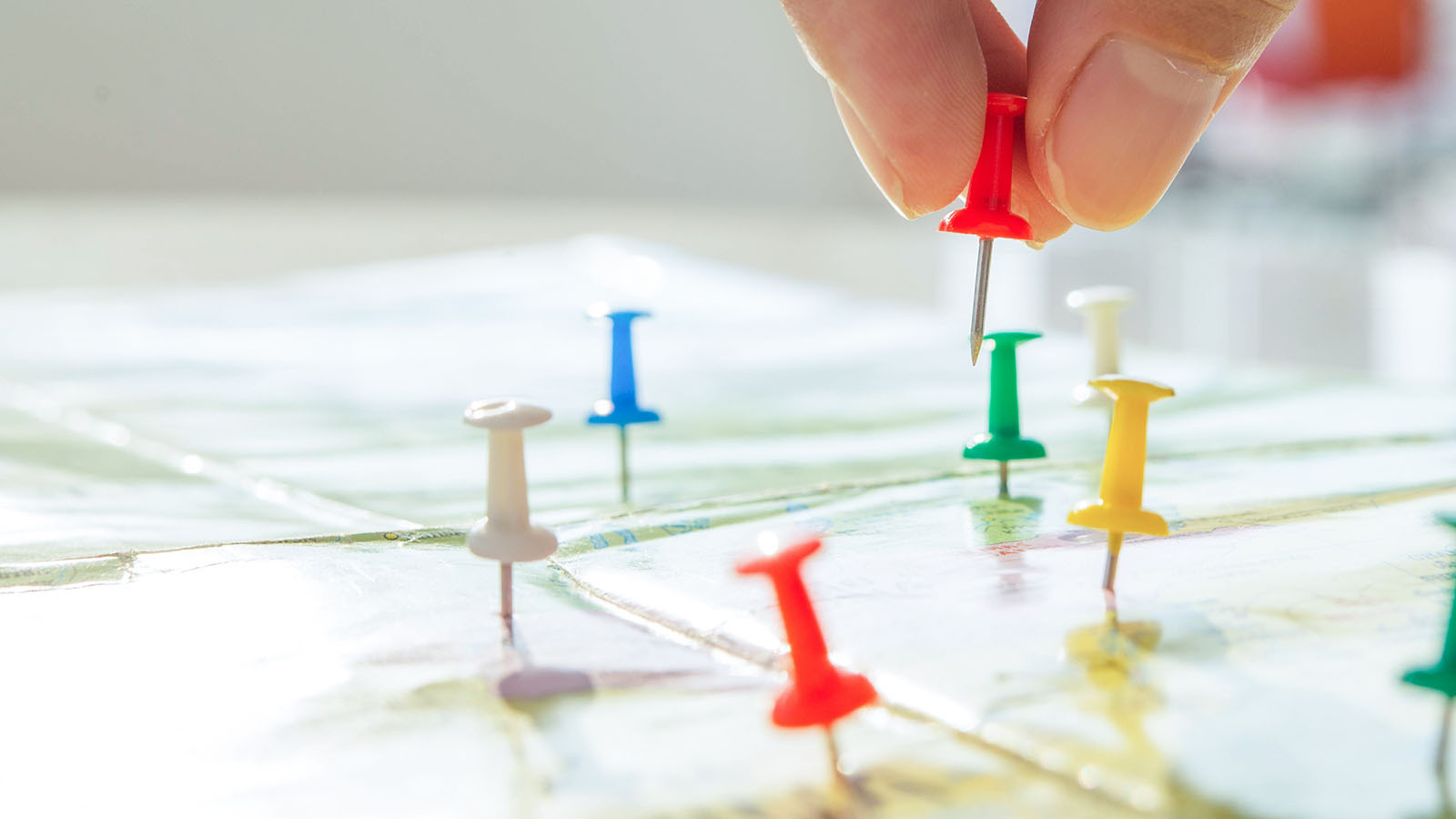Hand placing pins on a map of destination markets