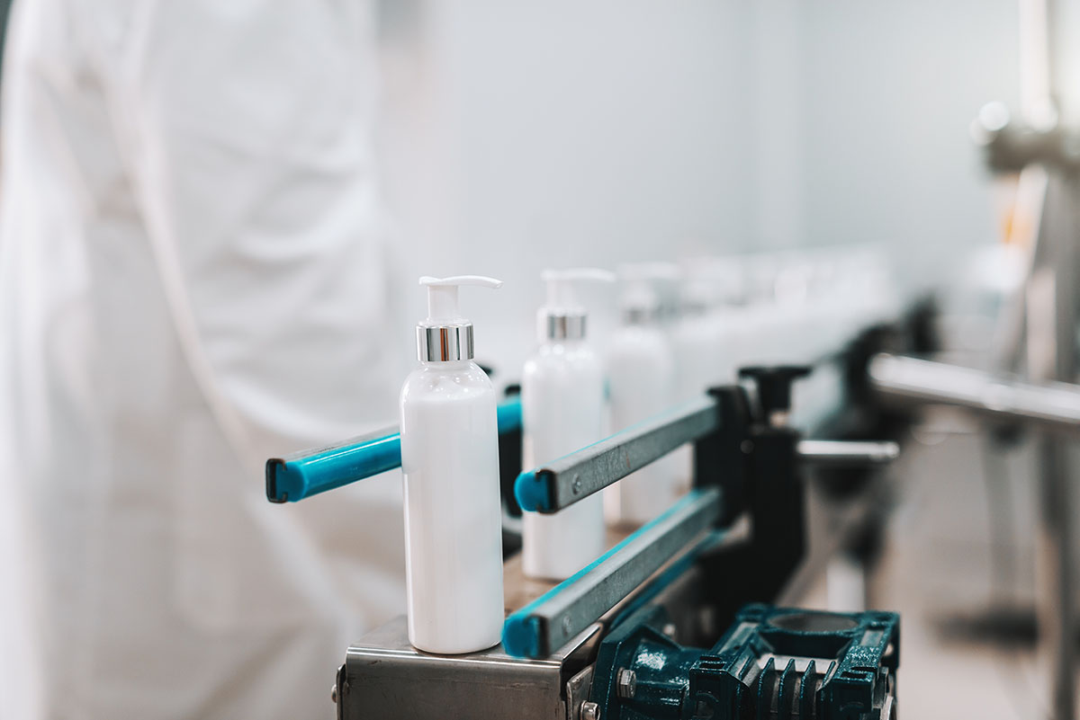 Rows of filled plastic bottles leaving a filling machine on a production line