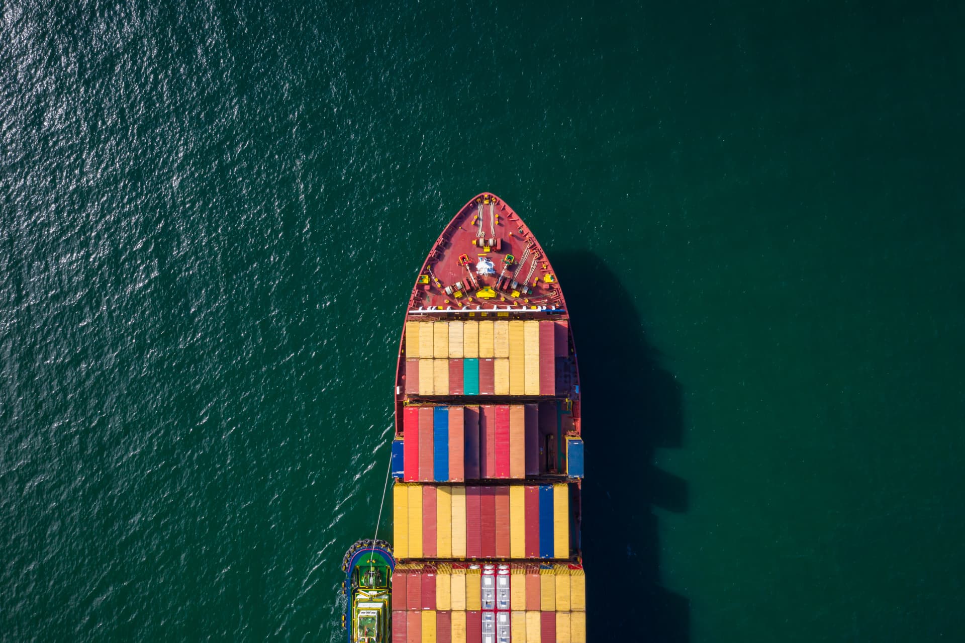 Container ship carrying export cargo across open sea, seen from above